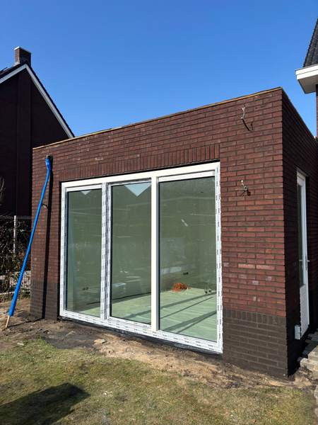 Aanbouw van donkere steen met schuifpui