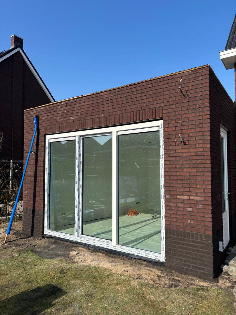 Aanbouw van donkere steen met schuifpui