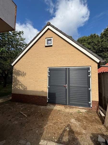Garage van gele steen met grijze deuren