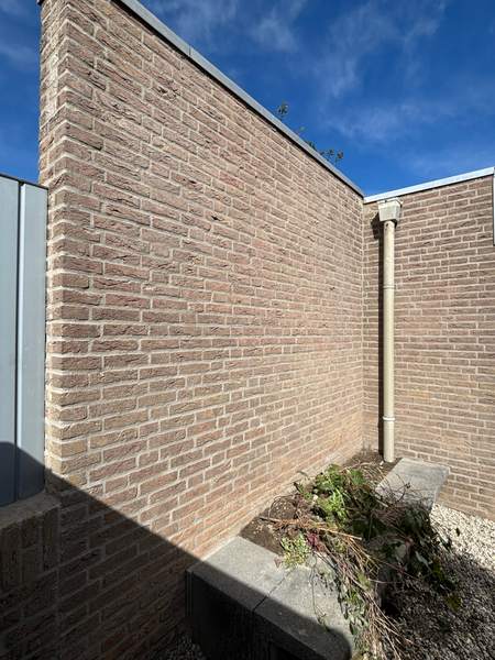 Binnenhoek van een bruine gevel met regenpijp
