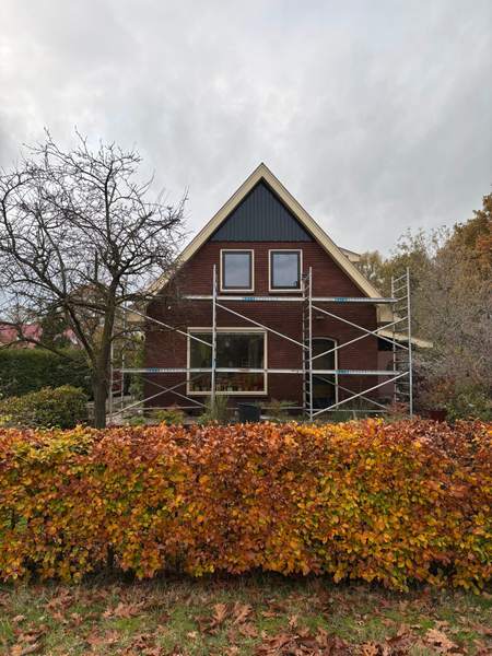 Woning met puntgevel in de steigers, gezien over de haag