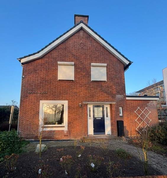 Vrijstaande woning in rode baksteen onder een blauwe lucht