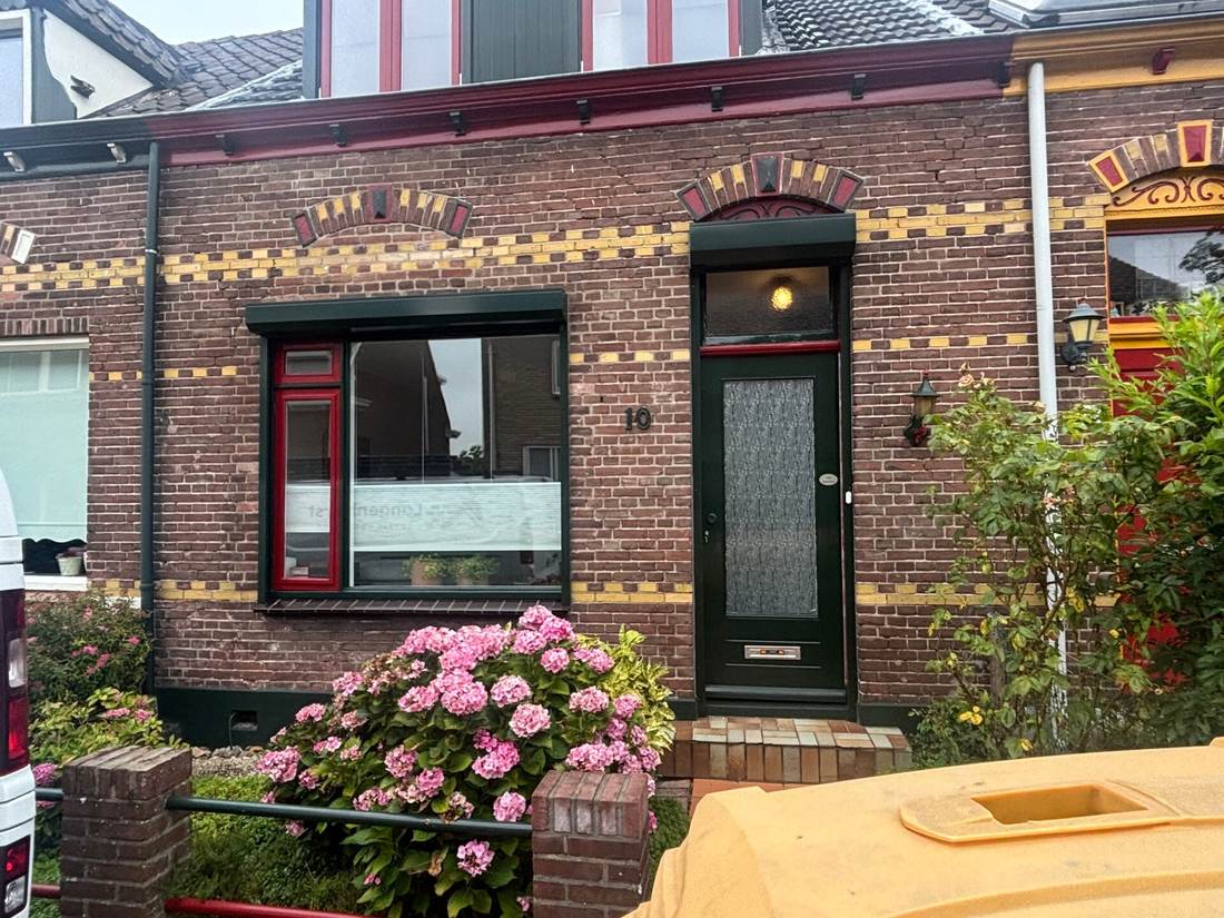 Voorgevel met sierlijsten en een rode voordeur