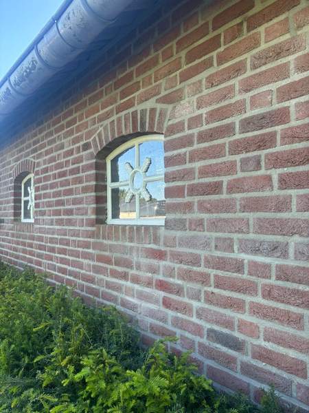Lange gevel met een rond raampje en strak voegwerk