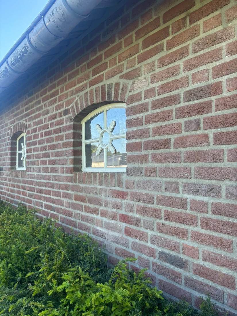 Lange gevel met een rond raampje en strak voegwerk