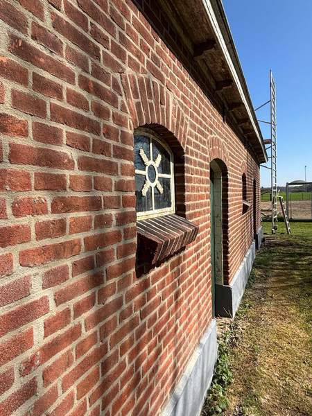 Gevel met rond raampje en luik, recht langs de muur gezien