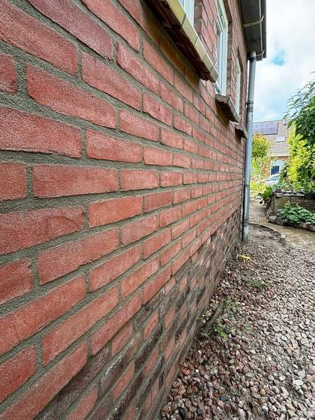 Zijmuur van rode baksteen langs een grindpad