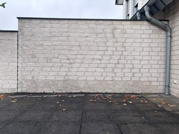 Dezelfde tuinmuur na de gevelreiniging, weer licht en schoon
