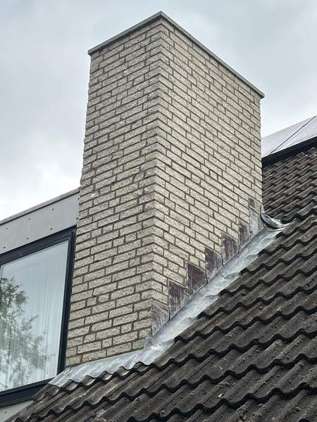 Hoge schoorsteen van lichte steen met loodaansluiting