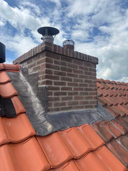 Schoorsteen op een rood pannendak met nieuw lood