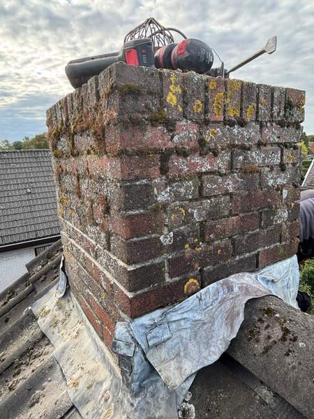 Oude schoorsteen met verweerd voegwerk, gereedschap op de rand