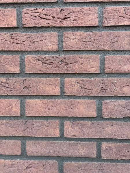 Rode baksteen met donkere voegen, recht van voren